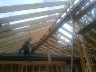 Rafters going up over a new addition with a worker on the wall in Piedmont