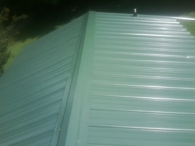 New green metal panels meeting at the ridge of a roof — Flat Roof Repair work by our crew in Piedmont